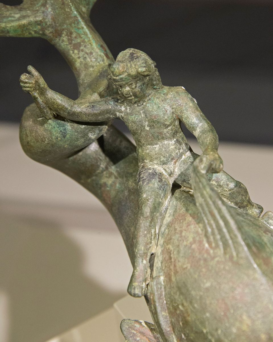 Estatuilla de bronce verdoso de Eros montado sobre un delfín, expuesta en una vitrina del museo arqueológico de Selçuk